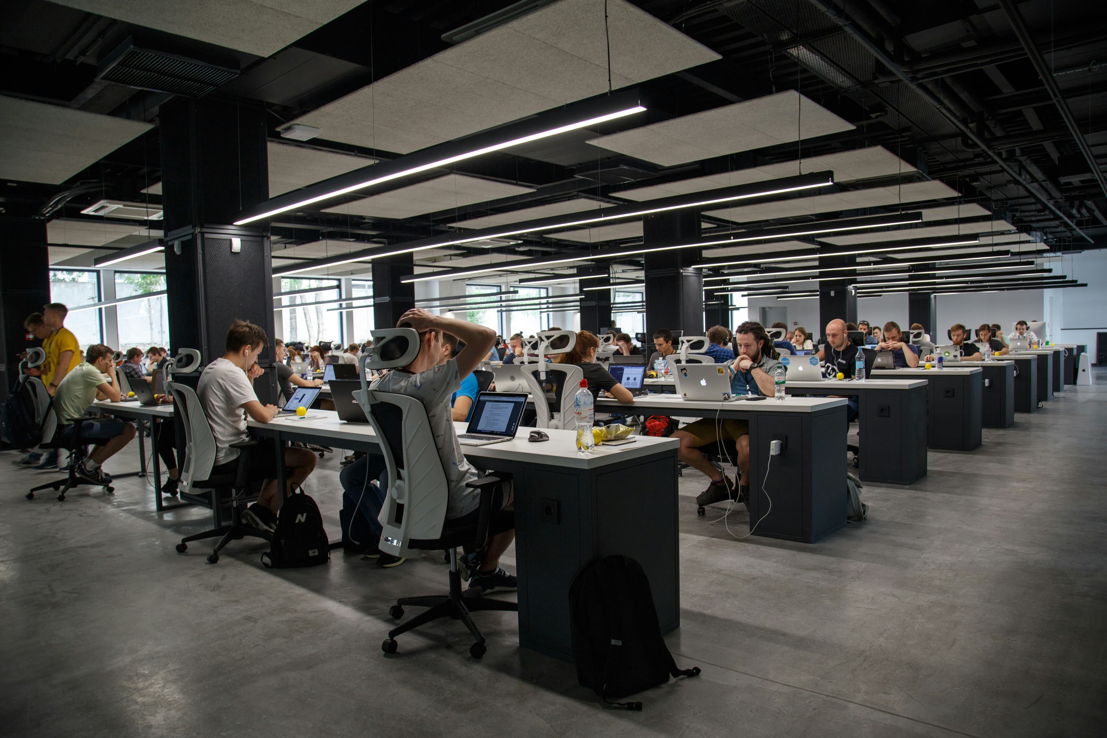 An open workspace with rows of people working at laptops